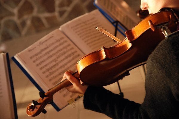 Violinist playing while reading music sheet.