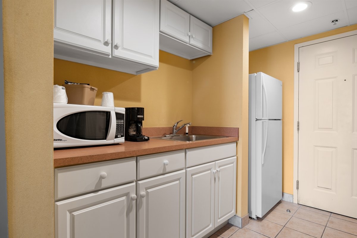 a kitchen with white cabinets and yellow walls